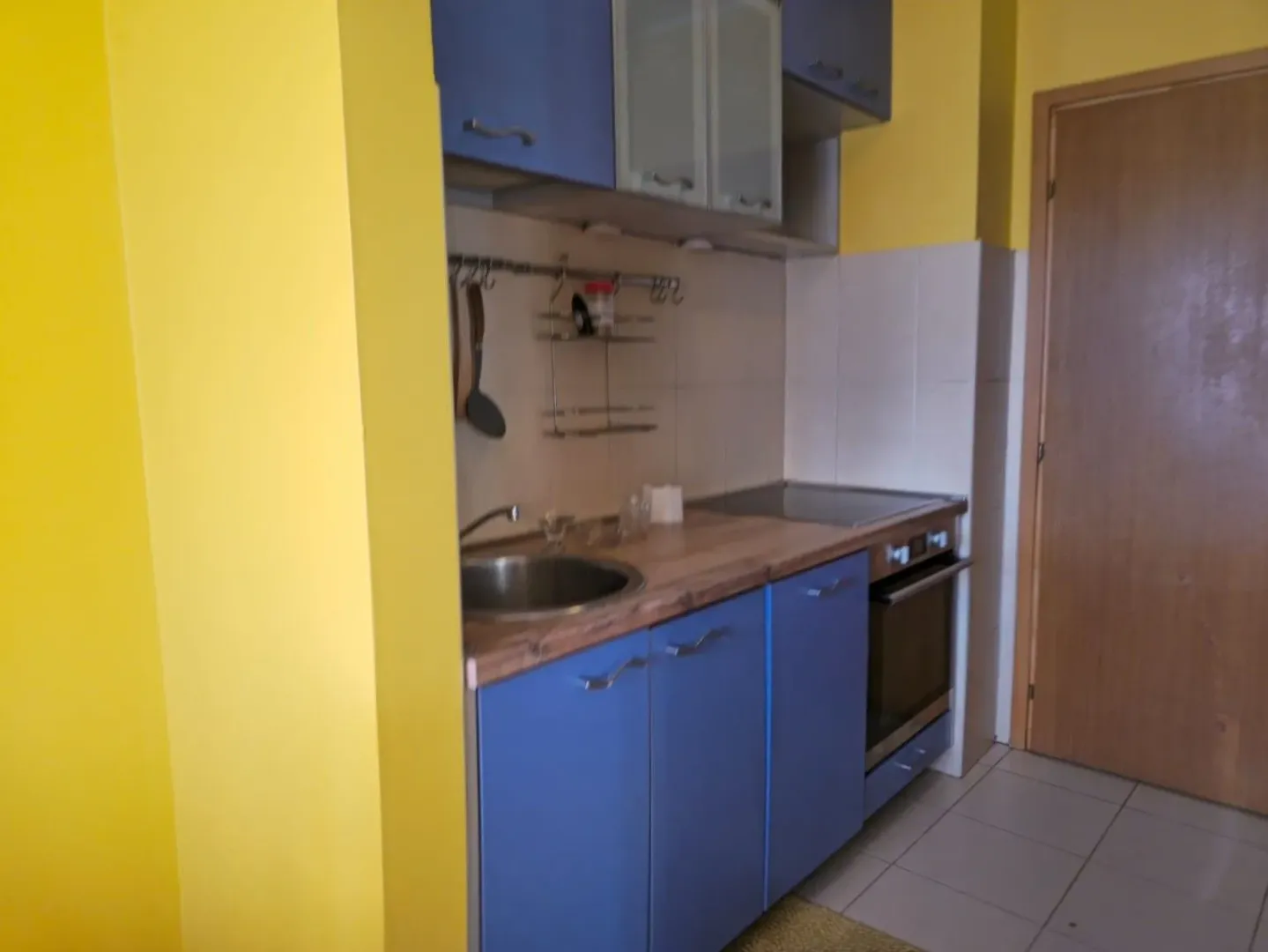 Small kitchen with blue cabinets and a built-in oven.
