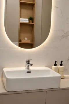 Beli umivaonik sa slavinom i osvetljenim ogledalom u modernom kupatilu. - image 19