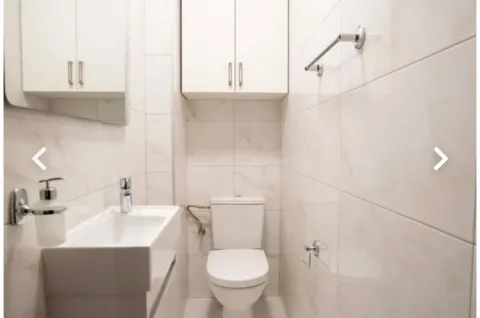 Manje kupatilo sa bijelim sanitarijama i svijetlim pločicama. - image 14