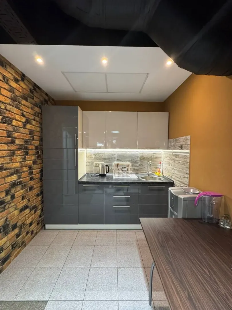 Smaller kitchen with grey elements and brick wall cladding.