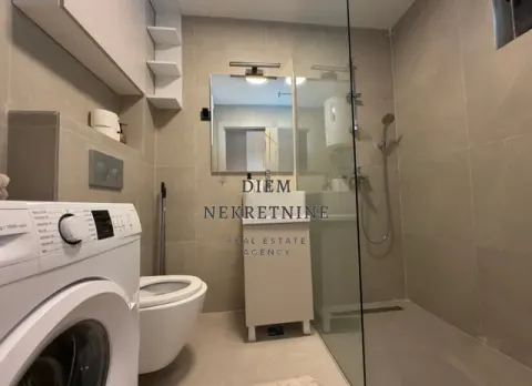 Modern bathroom with a walk-in shower, washbasin, and washing machine. - image 3