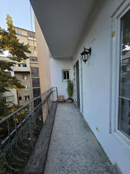 Long covered balcony with a metal railing and a view of neighboring buildings. - image 18