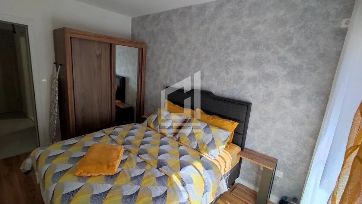 Furnished bedroom with a double bed, wardrobe, and a decorative wall.