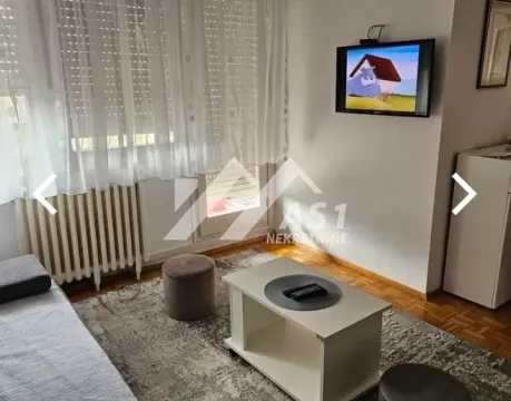 Living room with a sofa, coffee table, and a wall-mounted TV. - image 2