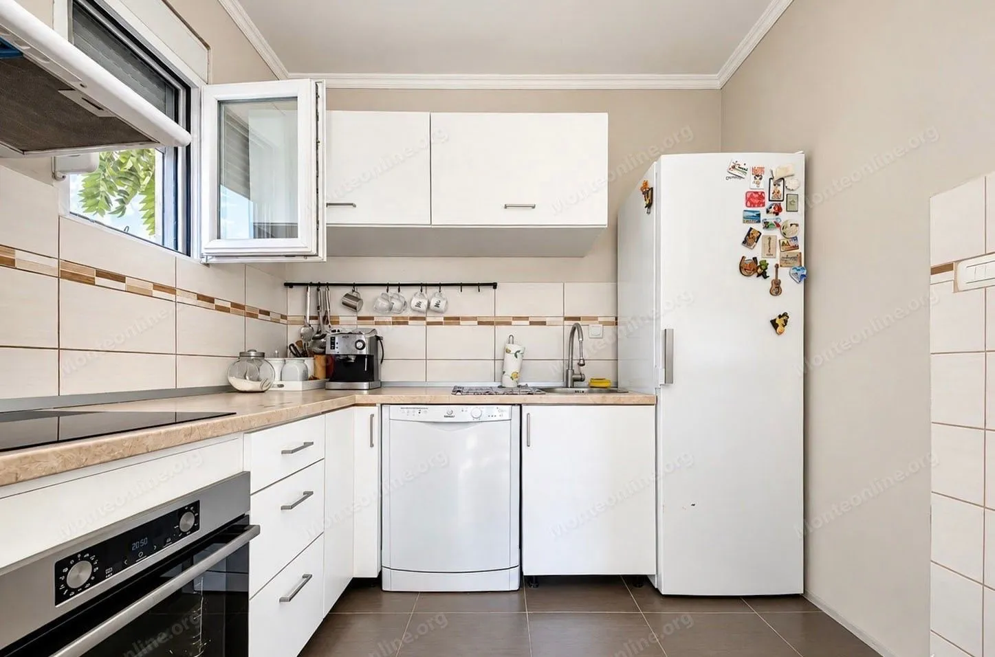 Small kitchen with white cabinets, built-in appliances, and a refrigerator.