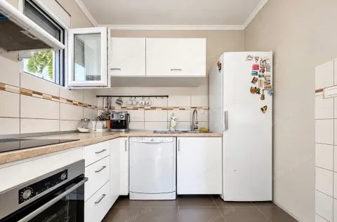 Small kitchen with white cabinets, built-in appliances, and a refrigerator. - image 14