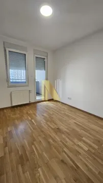 Prazna neopremljena soba sa drvenim parketom, prozorom i balkonskim vratima. - image 7