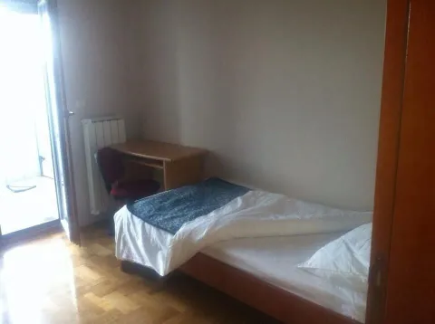 Jednostavna spavaća soba sa jednokrevetnim ležajem, radnim stolom i izlazom na balkon. - image 5