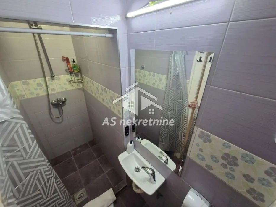 Small bathroom with a shower cabin, washbasin, and mirror.