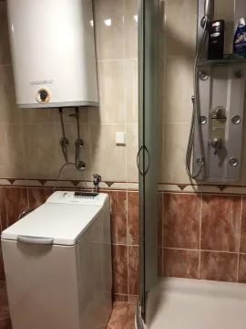 Bathroom with a shower cabin, water heater, and washing machine. - image 14