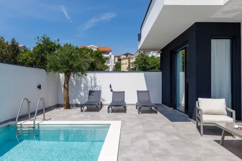 Yard with a swimming pool and sun loungers next to a modern house. - image 4