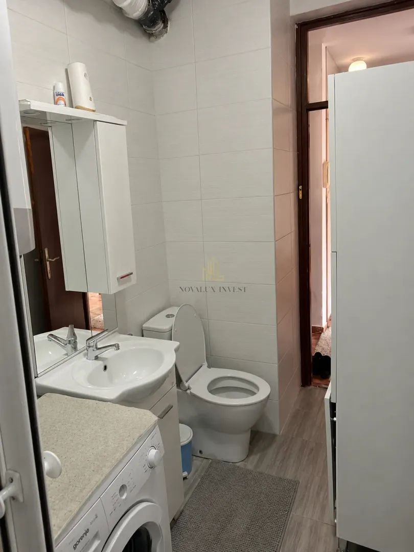 Manje kupatilo sa umivaonikom, WC šoljom, ogledalom i mašinom za veš.