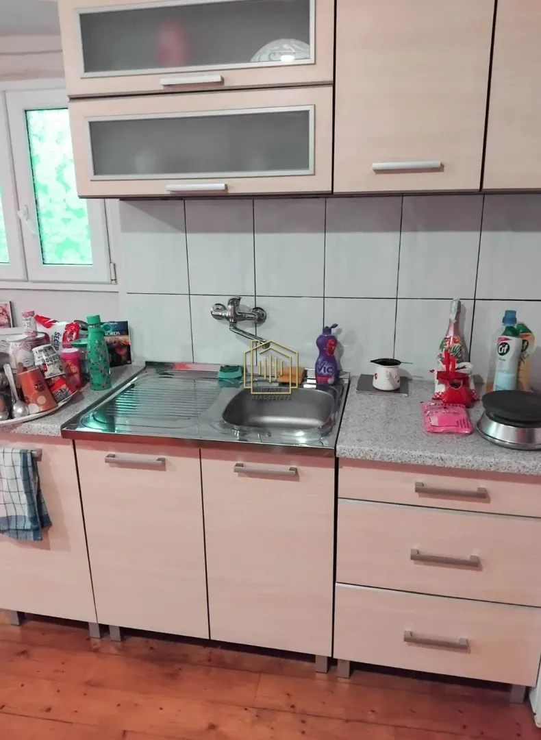 Manja kuhinja sa sudoperom i drvenim elementima.