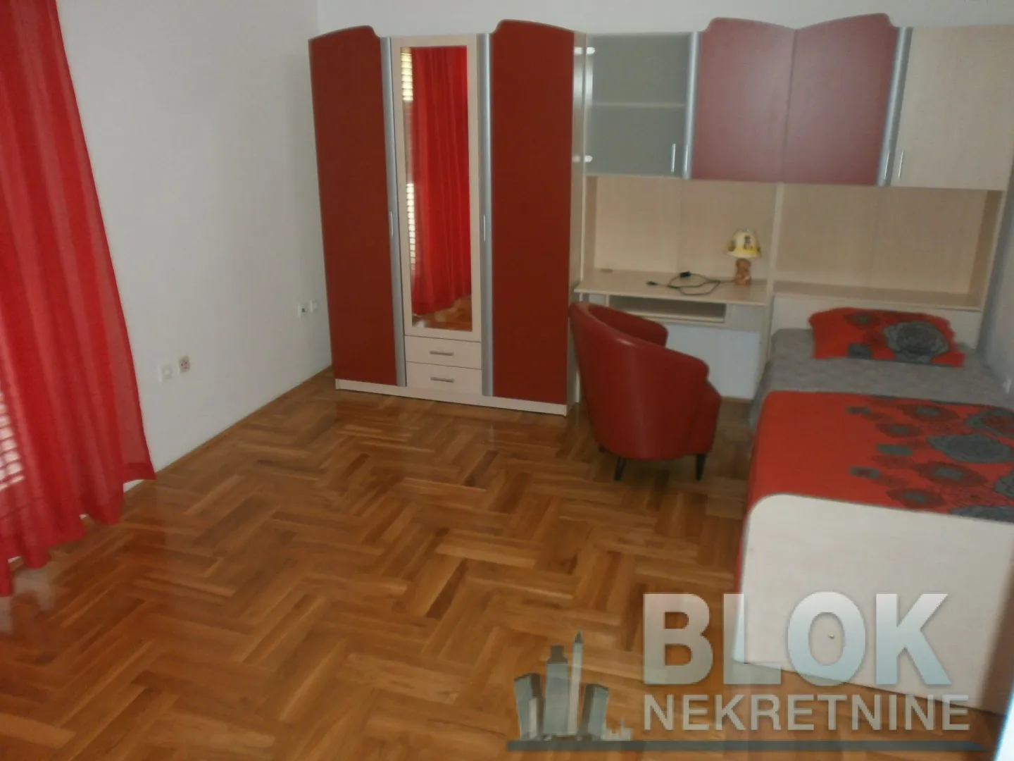 Bedroom with a bed, wardrobe, desk, and parquet flooring.