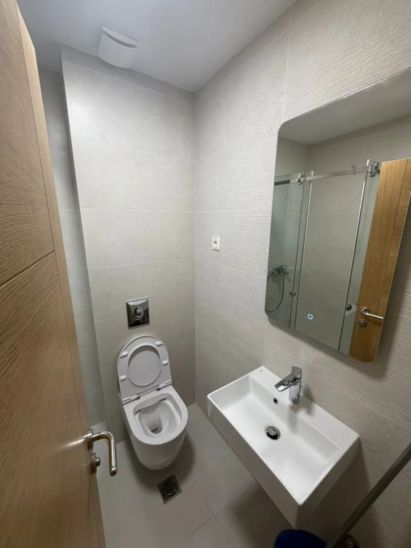 Modern bathroom with a wall-hung toilet, washbasin, and a large mirror.