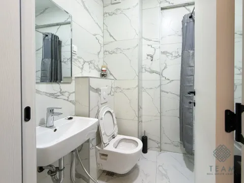 Small bathroom with white marble-effect tiles, a sink, and a walk-in shower. - image 9