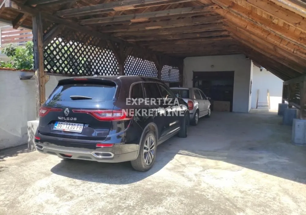 Covered parking area with a wooden structure and parked cars.