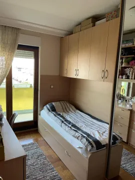 Svijetla jednokrevetna spavaća soba sa ugradnim drvenim ormarom i izlazom na balkon. - image 14
