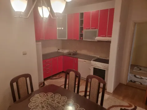 Manja kuhinja sa crvenim elementima i trpezarijskim stolom u prvom planu. - image 8