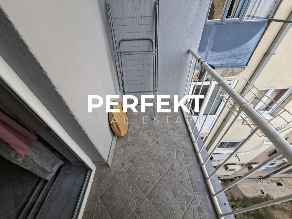 Manji popločani balkon sa ogradom i stalkom za sušenje veša.