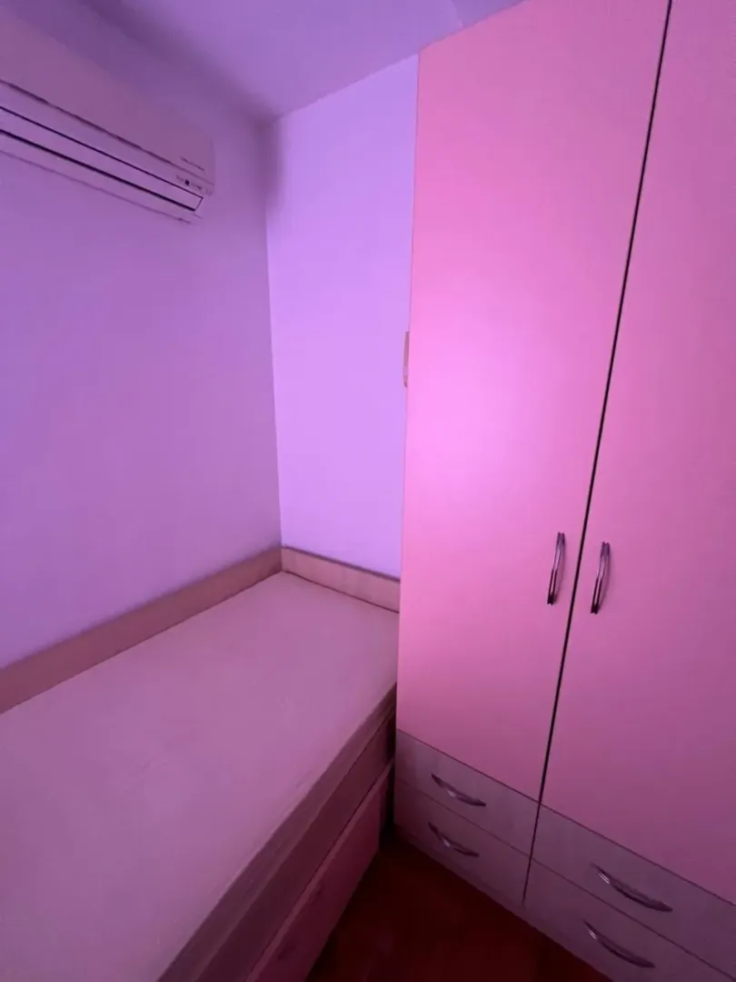 Manja spavaća soba sa krevetom i roze garderoberom.