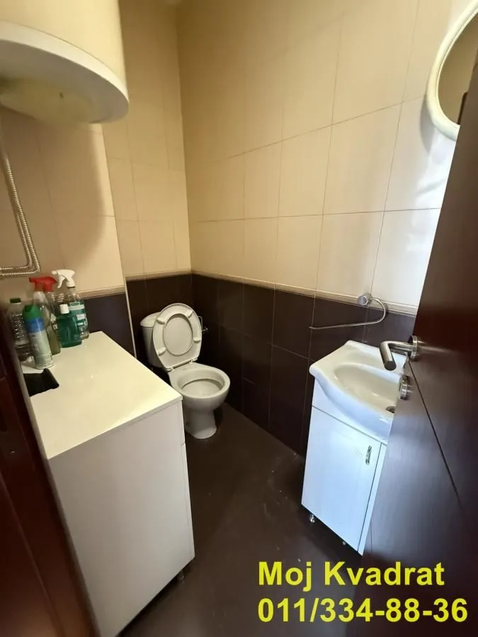 Smaller bathroom with a toilet, washbasin, and water heater.