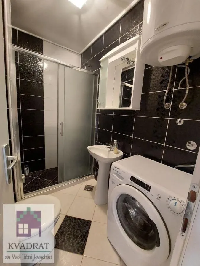 Bathroom with a shower cabin, washbasin, and washing machine.