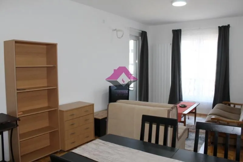 Living room with sofa, dining table, and shelving units.
