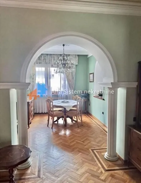 View through a decorative archway into the dining room with a wooden table and chairs.