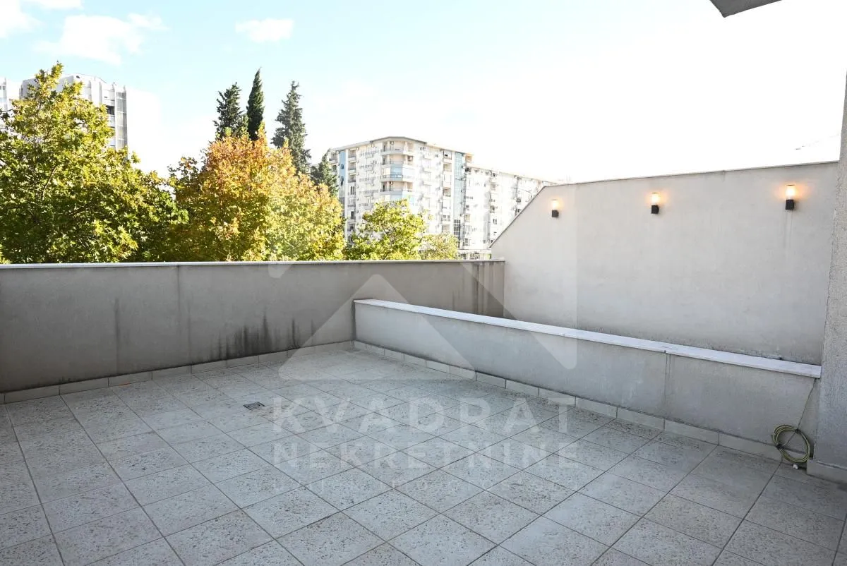 Spacious tiled terrace with wall lighting and a view of the urban neighborhood.