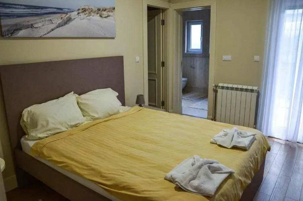 Udobna spavaća soba sa bračnim krevetom i pogledom na kupatilo.