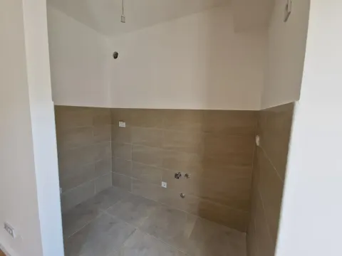Prazan kuhinjski prostor sa zidnim pločicama i pripremljenim priključcima za vodu. - image 6