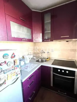 Smaller kitchen with purple cabinets and built-in appliances. - image 6
