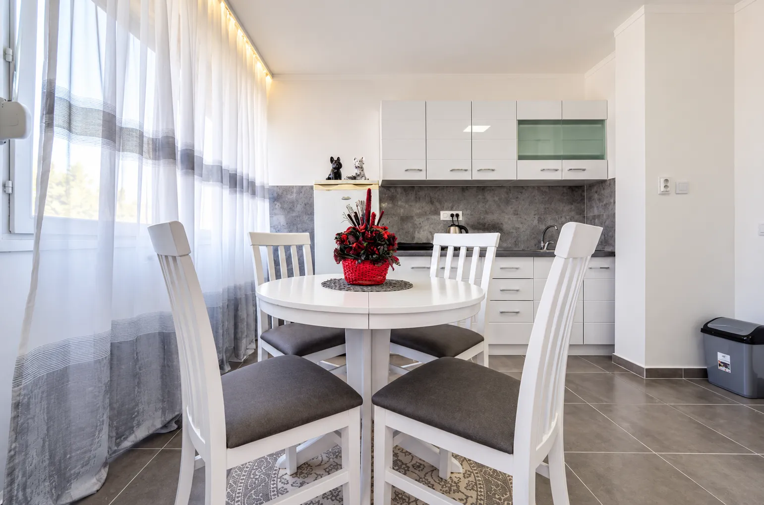 Dining table with white chairs as part of the kitchen area.