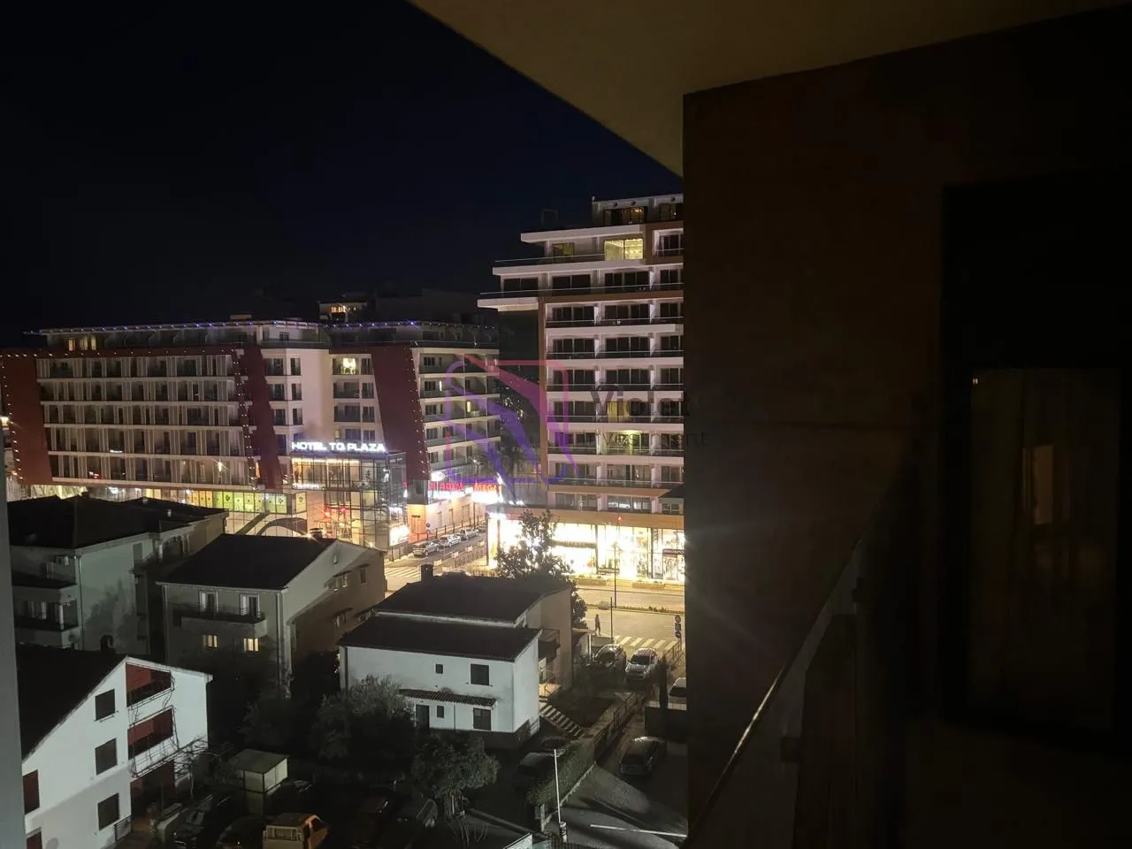 Noćni pogled sa terase na gradske ulice i okolne zgrade.