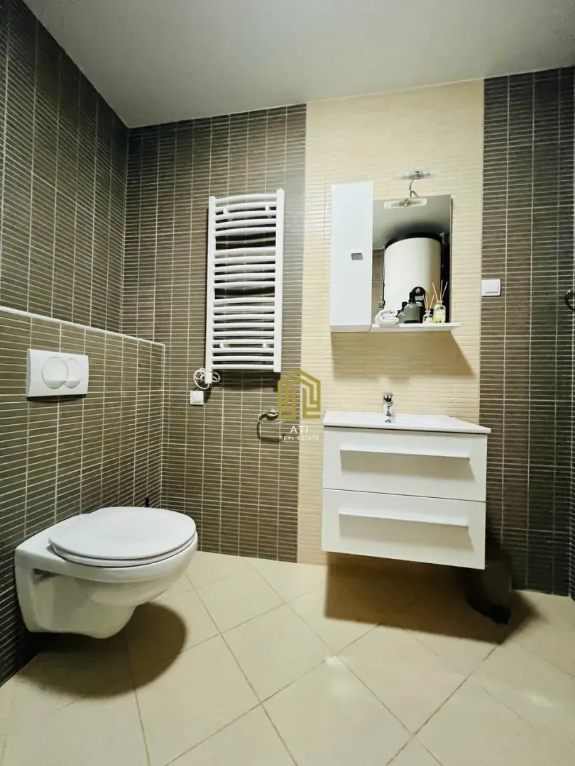 Modern bathroom equipped with a sink, toilet bowl, and tiles.