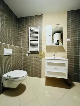 Modern bathroom equipped with a sink, toilet bowl, and tiles. - image 9