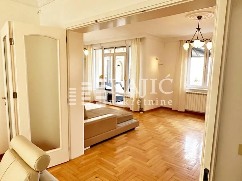 View from the hallway into a bright living room with parquet flooring.