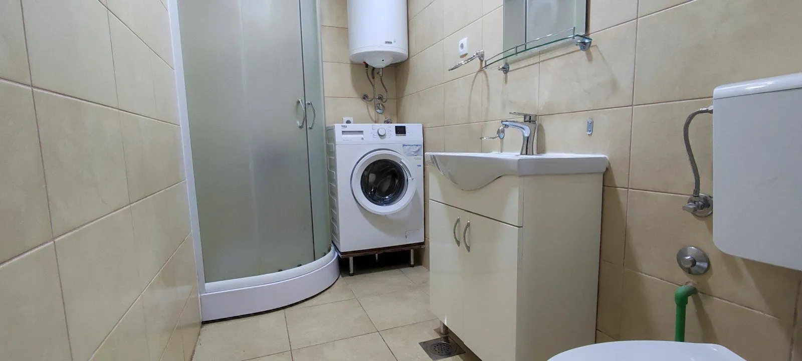 Bathroom with a shower cabin, sink, and washing machine.
