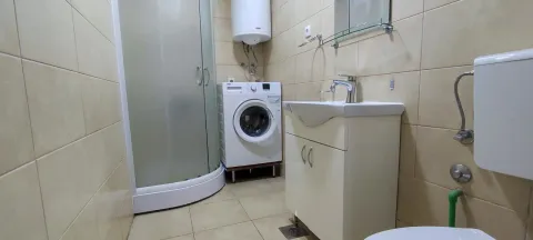 Bathroom with a shower cabin, sink, and washing machine. - image 12
