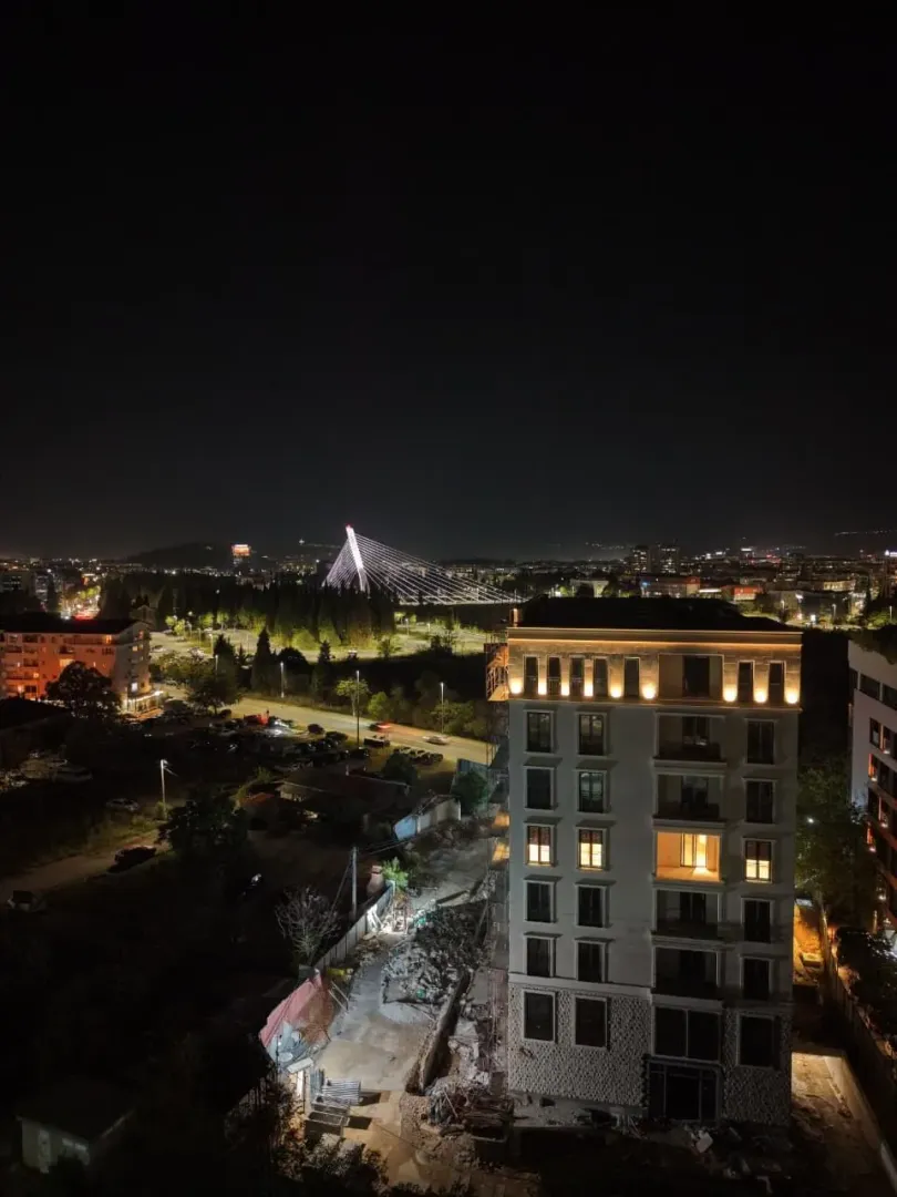 Noćni pogled sa terase na grad i osvijetljeni most.