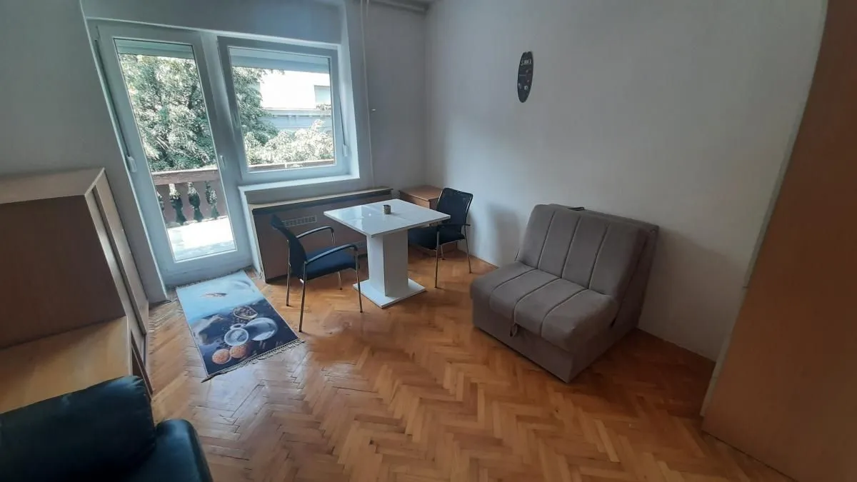 Dnevna soba sa garniturom za sedenje, trpezarijskim stolom i izlazom na terasu.