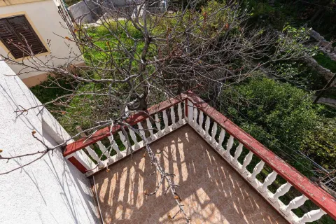 Pogled odozgo na popločanu terasu sa ogradom i drvetom u dvorištu. - image 26