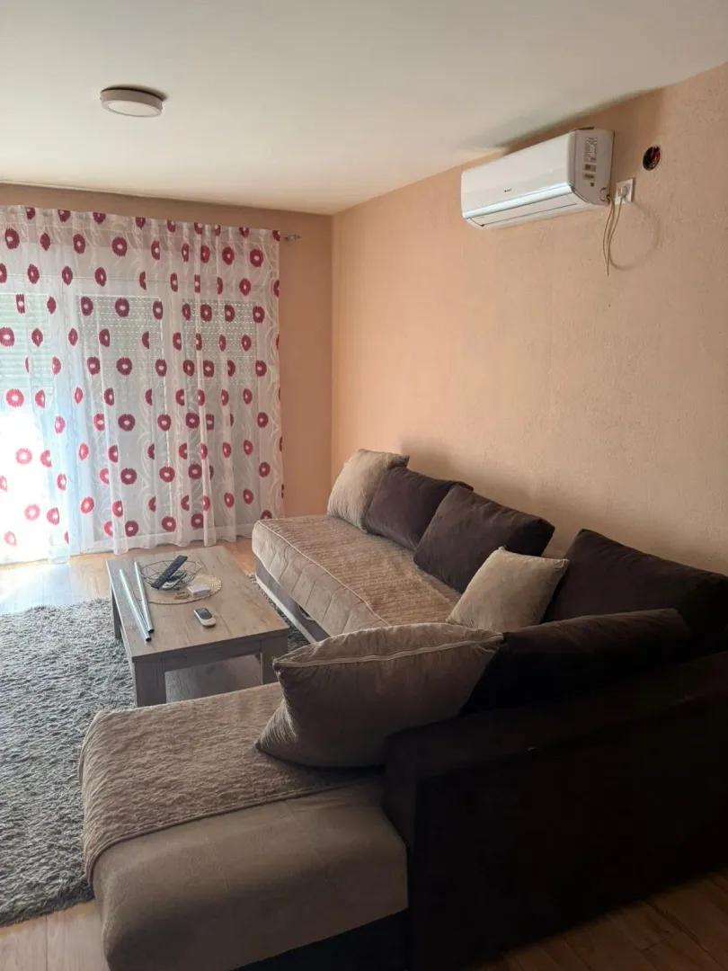 Living room with a sectional sofa, coffee table, and air conditioning unit.