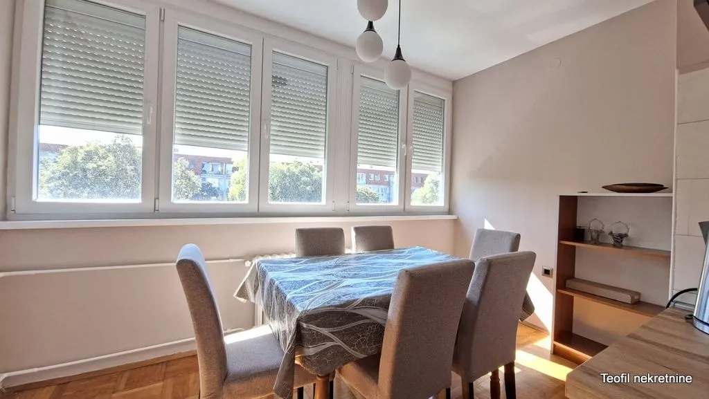 Dining area with a table, chairs, and large windows.