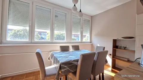 Dining area with a table, chairs, and large windows. - image 7