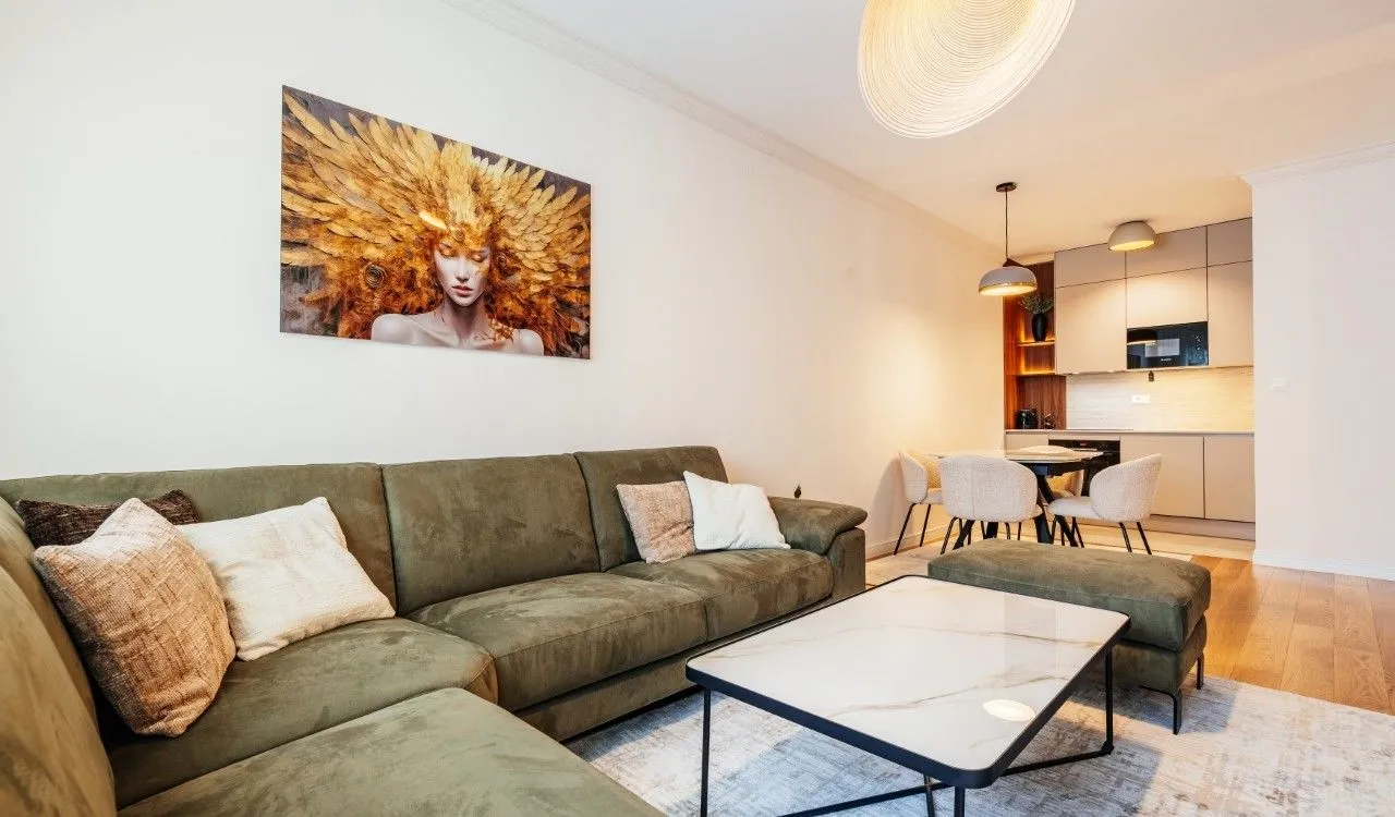 Living room with a sofa and a view towards the dining area and kitchen in the background.