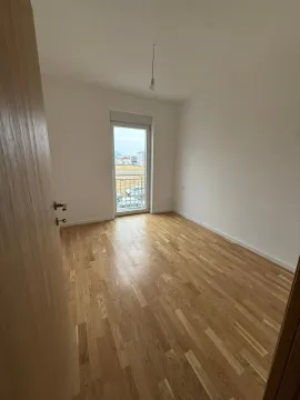 Prazna soba sa drvenim parketom i balkonskim vratima. - image 3