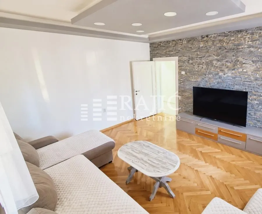 Living room with a sofa, TV unit, and decorative stone wall.