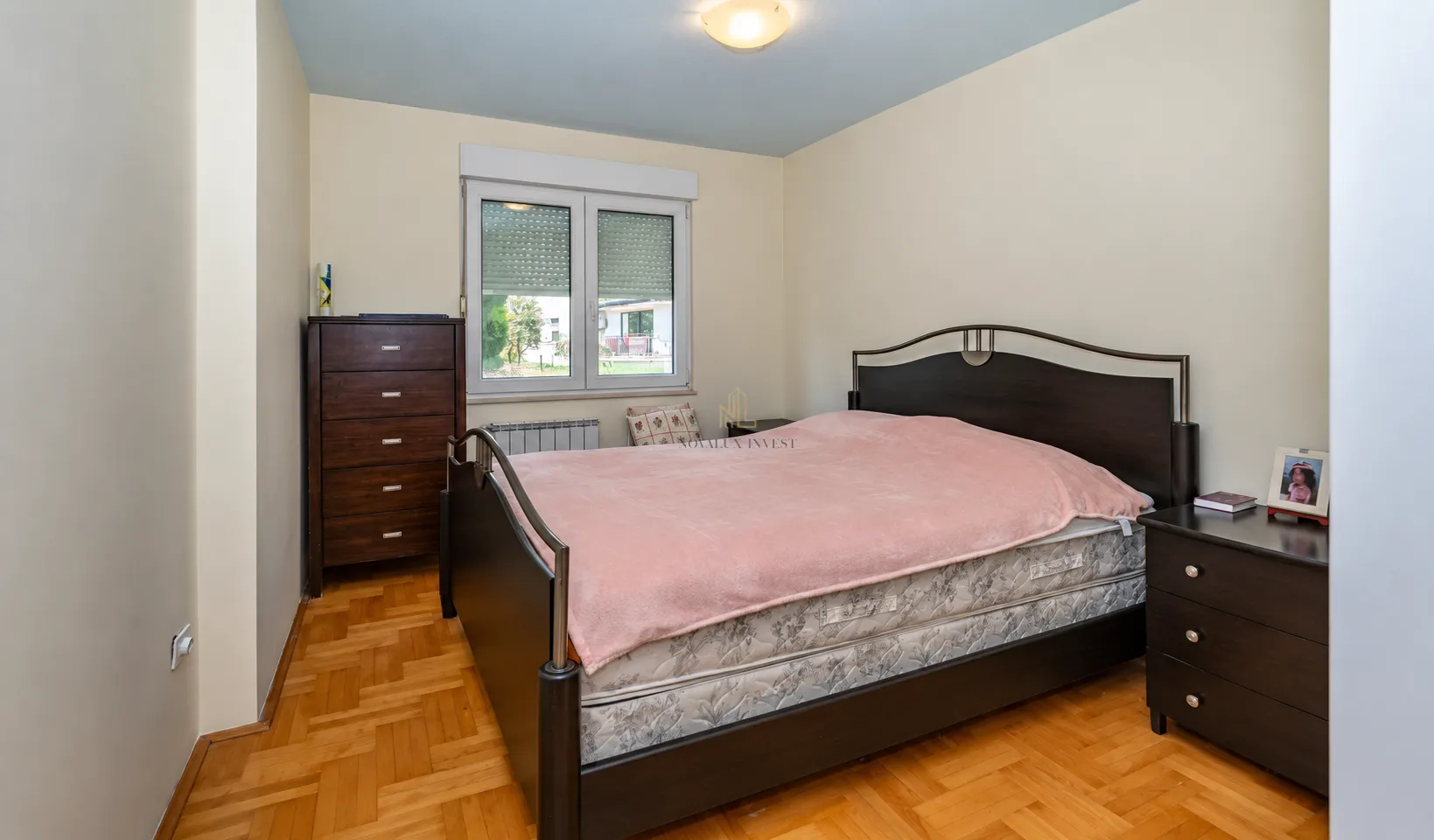 Bedroom with a double bed, wooden parquet flooring, and dark wooden furniture.